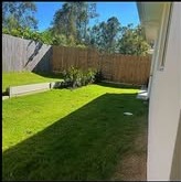 Mowed two-level backyard with a low retaining wall and wood fence